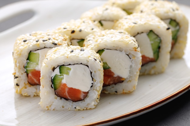 Rollo de sushi con salmón, queso philadelphia y sésamo en placa de cerca