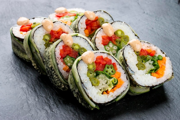 Rollo de sushi con verduras sobre fondo negro Plato vegetariano
