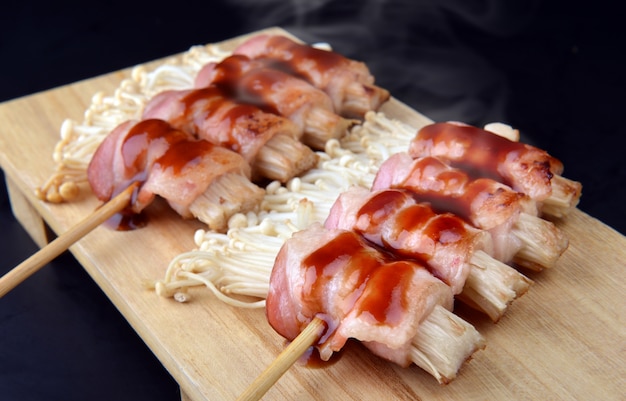 Rollo de tocino con setas enoki a la parrilla.