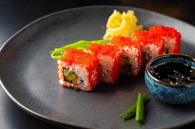 Rollos asiáticos tradicionales y sushi con salsa de soja y wasabi servidos en un fondo oscuro