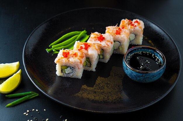 Rollos asiáticos tradicionales y sushi con salsa de soja y wasabi servidos en un fondo oscuro