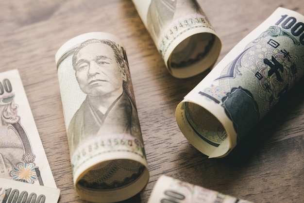 Rollos de billetes de dinero yen japonés en mesa de madera