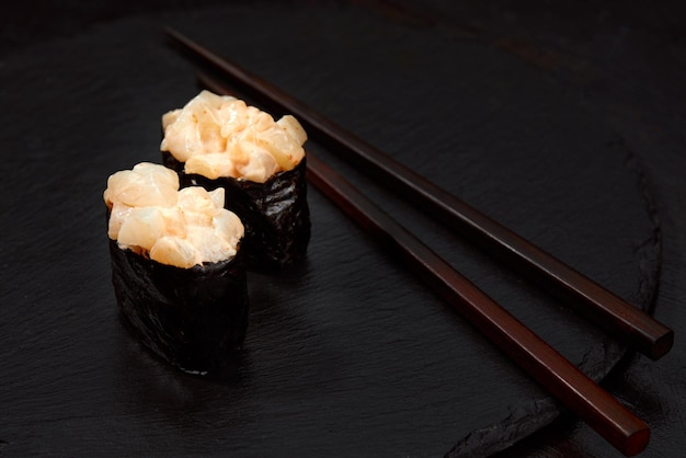 Rollos calientes con atún salmón perca anguila tobiko caviar nori arroz pepino sobre fondo negro