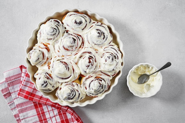 Rollos de canela o bollos de postre tradicionales dulces caseros de cinnabon con salsa de crema blanca en g blanco