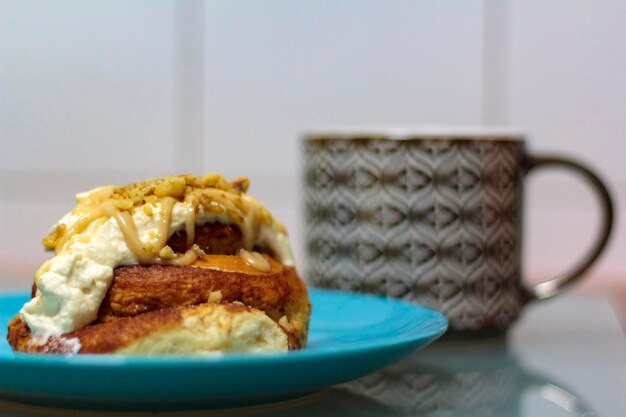 Rollos de canela con queso crema y taza de té en el fondo