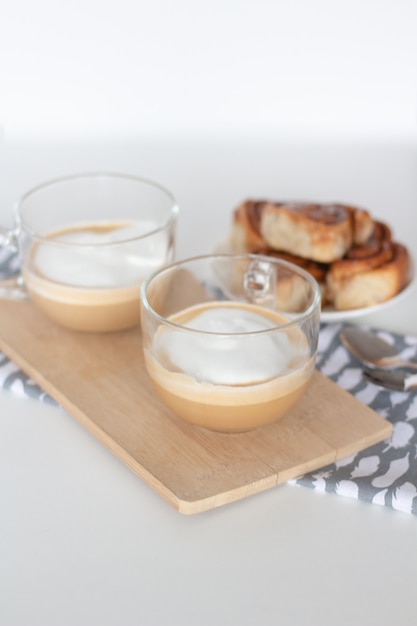 Rollos de canela y una taza de café sobre fondo blanco.