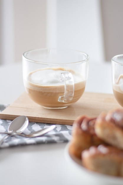 Rollos de canela y una taza de café sobre fondo blanco.