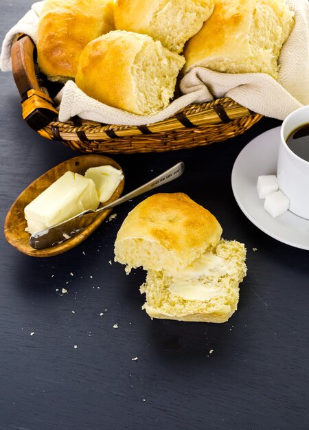 Rollos de cena de masa fermentada recién horneados sobre fondo negro.