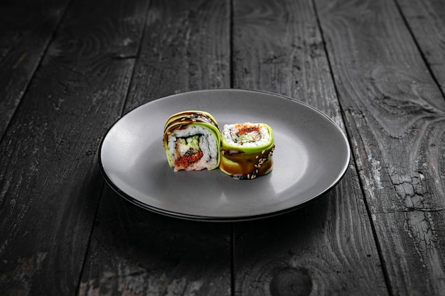 Rollos de cocina japonesa sobre un plato redondo sobre una mesa negra