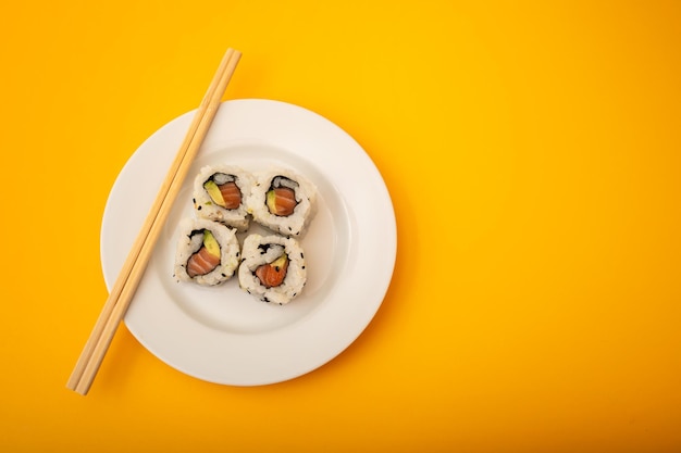 Rollos de comida japonesa con pescado y aguacate en plato blanco