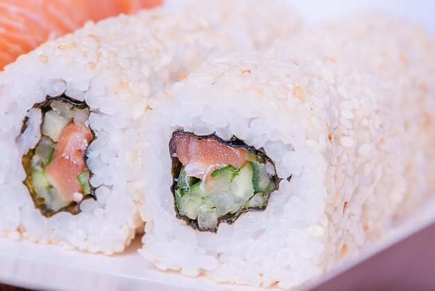 Rollos de comida japonesa en sésamo con salmón, pepino, queso Filadelfia Comida a domicilio