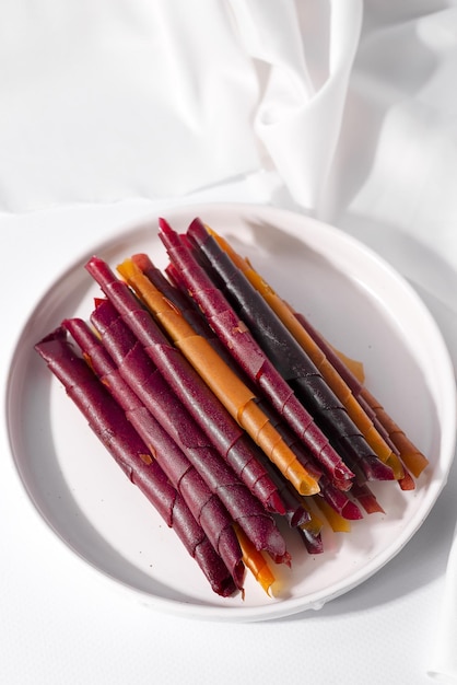 Rollos de cuero de frutas de colores en un plato sobre fondo claro