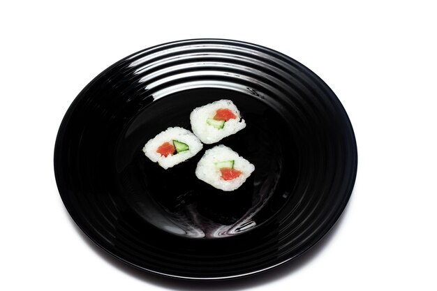 Foto rollos japoneses en un plato negro aislado