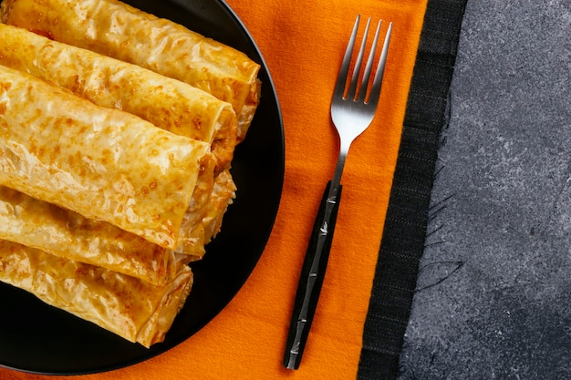 Foto rollos de masa filo crujiente recién horneados servidos en una placa negra