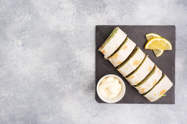 Rollos de pan de pita fino y salmón rojo salado con hojas de lechuga Sobre un soporte de pizarra, mesa de hormigón gris. Copie el espacio.