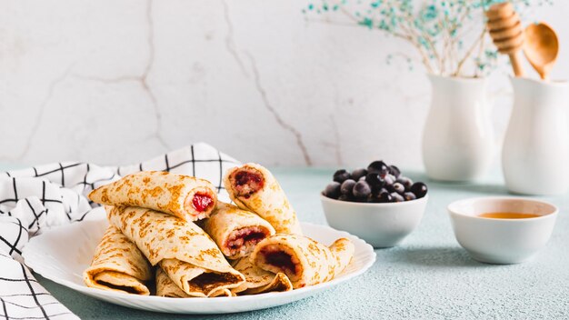 Rollos de panqueque caseros con relleno de bayas en un plato en la mesa