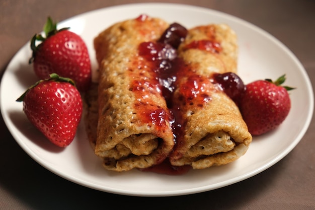 Rollos de panqueques con mermelada de bayas y fresas frescas decoradas