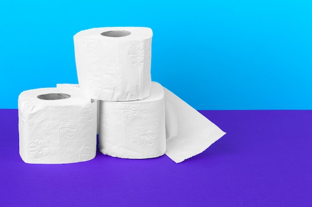 Rollos de papel higiénico aislados en mesa blanca con púrpura