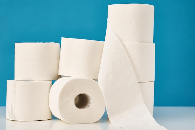 Rollos de papel higiénico apilados sobre un fondo azul concepto de higiene