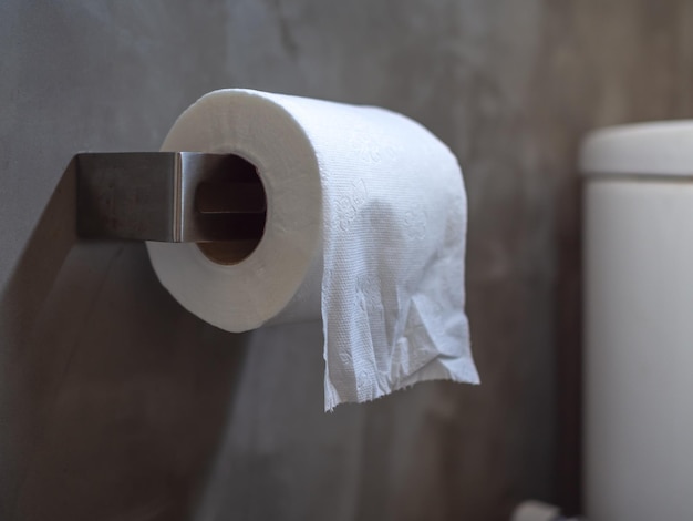 Rollos de papel higiénico blanco y limpio en el baño sobre fondo de pared de hormigón