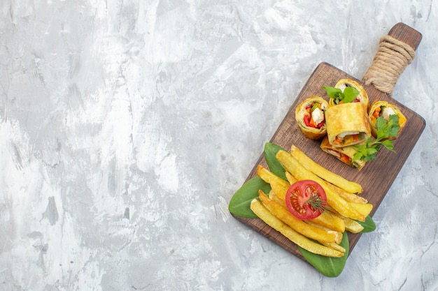 Rollos de paté de verduras de vista superior con papas fritas sobre superficie blanca