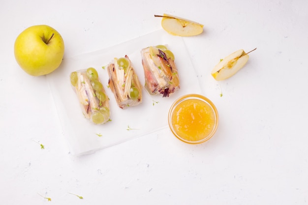 Rollos de primavera dulces de fruta junto a una manzana fresca en blanco. Hay un lugar para el texto