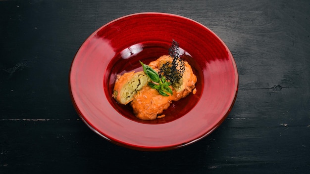 Rollos de repollo con salsa de tomate en un plato rojo Sobre una mesa de madera Vista superior Espacio de copia