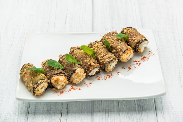 Rollos de rodajas de berenjena a la parrilla con queso feta y tomate y salsa Tzatziki closeup