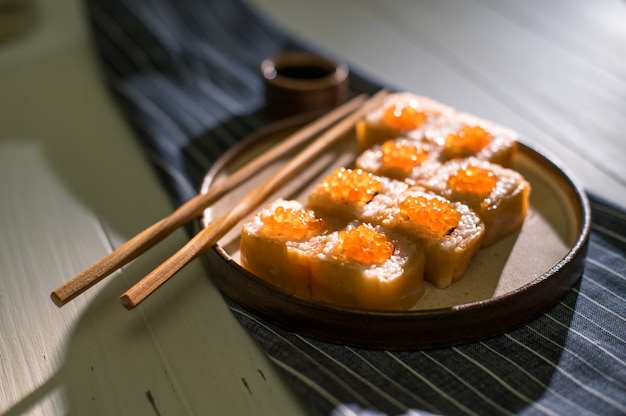 Rollos de salmón y caviar servidos en una placa blanca.