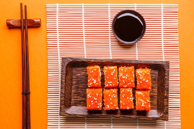 Rollos, salsa de soja, palillos en la mesa naranja, tapa fotográfica