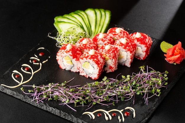 Rollos de sushi con aguacate, camarones y queso crema en negro