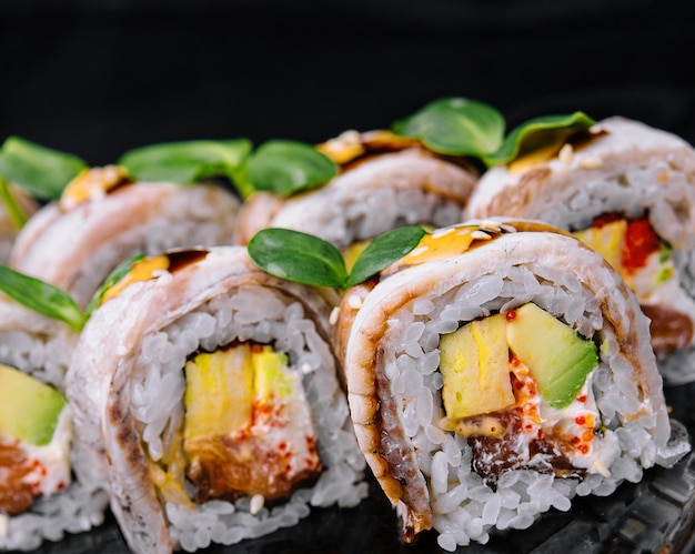 Rollos de sushi de anguila en plato negro