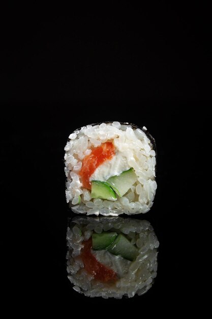 Rollos de sushi con arroz, salmón y pepino sobre fondo negro con reflejo