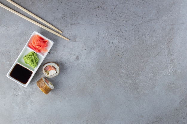 Rollos de sushi con atún, wasabi, jengibre y salsa de soja sobre fondo de piedra.