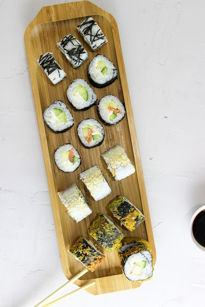 Rollos de sushi en una bandeja de madera con salsa de soja