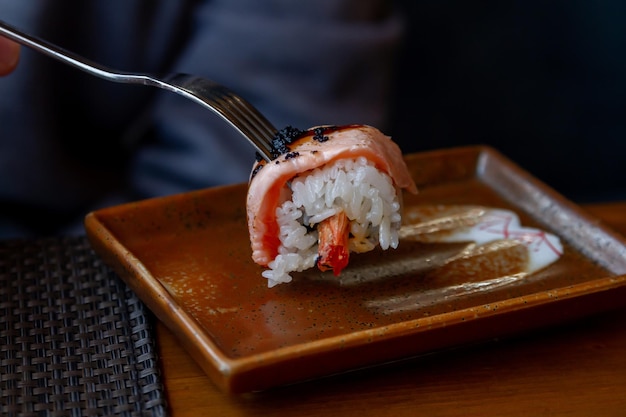 Los rollos de sushi de comida japonesa se comen con un primer plano de dispositivo europeo, la comida japonesa se ensarta