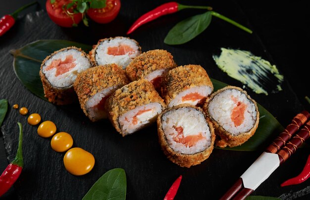 Foto rollos de sushi de comida tradicional japonesa y salsa sobre fondo negro vista superior