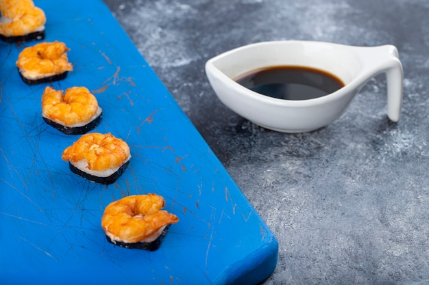 Rollos de sushi delicioso fresco con camarones colocados sobre una tabla de cortar de madera.