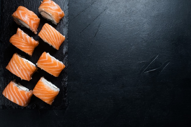 Rollos de sushi de Filadelfia sobre fondo oscuro. Arte de fotografía de alimentos. Concepto de espacio libre