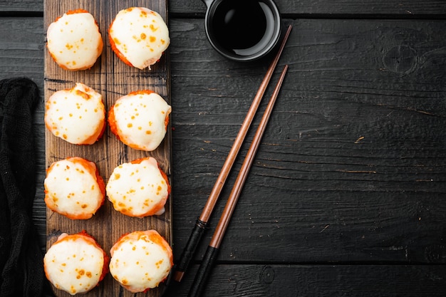 Rollos de sushi fresco con wasabi y jengibre, sobre mesa de madera negra