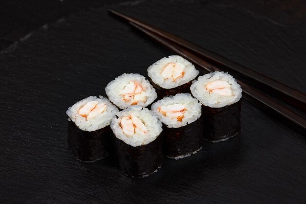 Rollos de sushi frescos deliciosos tradicionales con camarones sobre un fondo negro Rollo de sushi con arroz queso crema aguacate salmón sésamo Menú de sushi Restaurante de cocina japonesa