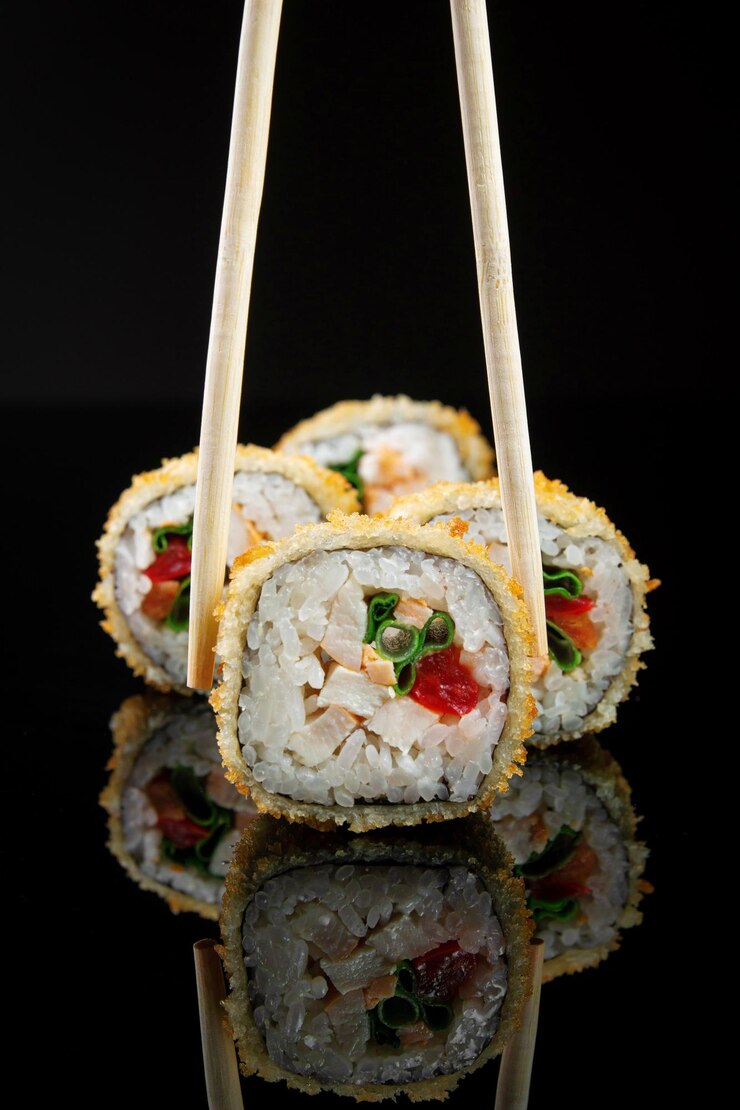 Rollos de sushi fritos con pollo de arroz y hierbas en un fondo negro con reflejo