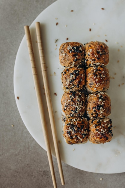 Rollos de sushi horneados en una tabla de servir de mármol y espolvoreados con semillas de sésamo