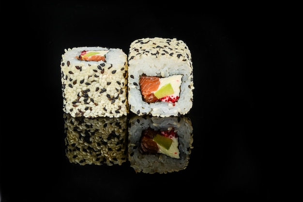 Rollos de sushi japonés fresco tradicional sobre un fondo negro