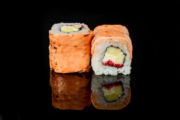 Rollos de sushi japonés fresco tradicional sobre un fondo negro