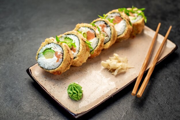 Rollos de sushi japonés horneado sobre un fondo de piedra listo para comer