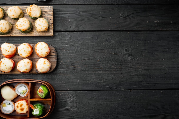 Rollos de sushi japonés llamado Baked Ebi con wasabi y salmón, sobre mesa de madera negra