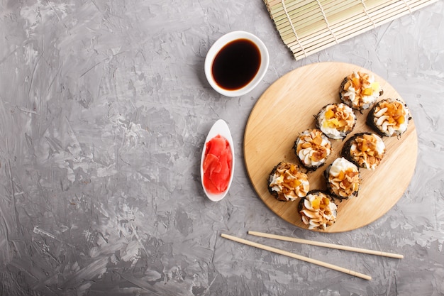 Rollos de sushi maki japonés con queso crema sobre tabla de madera sobre hormigón gris