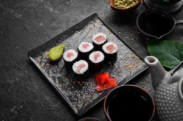 Rollos de sushi maki con salmón en un plato de piedra negra Vista superior