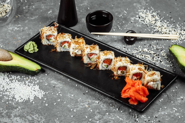 Rollos de sushi con queso crema, salmón frito, virutas de atún o bonito seco, pepino, nori. Palillos con rollo de katsuobushi fresco en el primer plano del restaurante japonés.